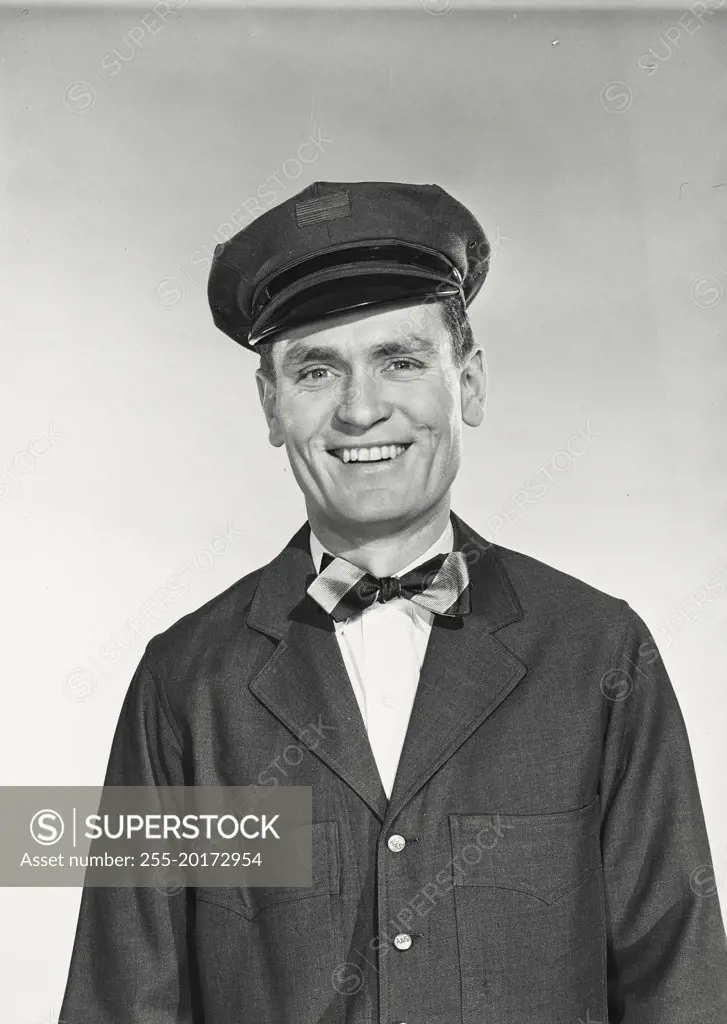 Vintage photograph. Mailman in uniform with hat and bow tie smiling