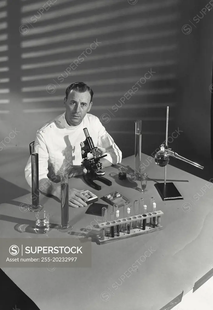 Scientist holding case of slides and sitting at microscope