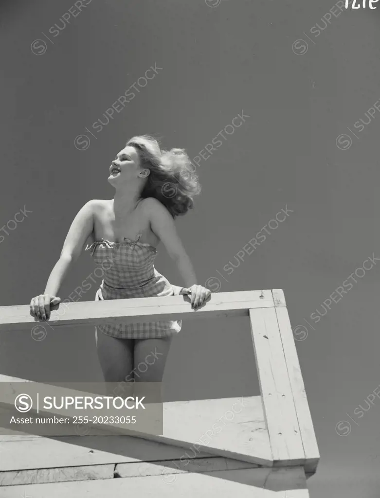 Woman in short dress leaning over railing of the deck