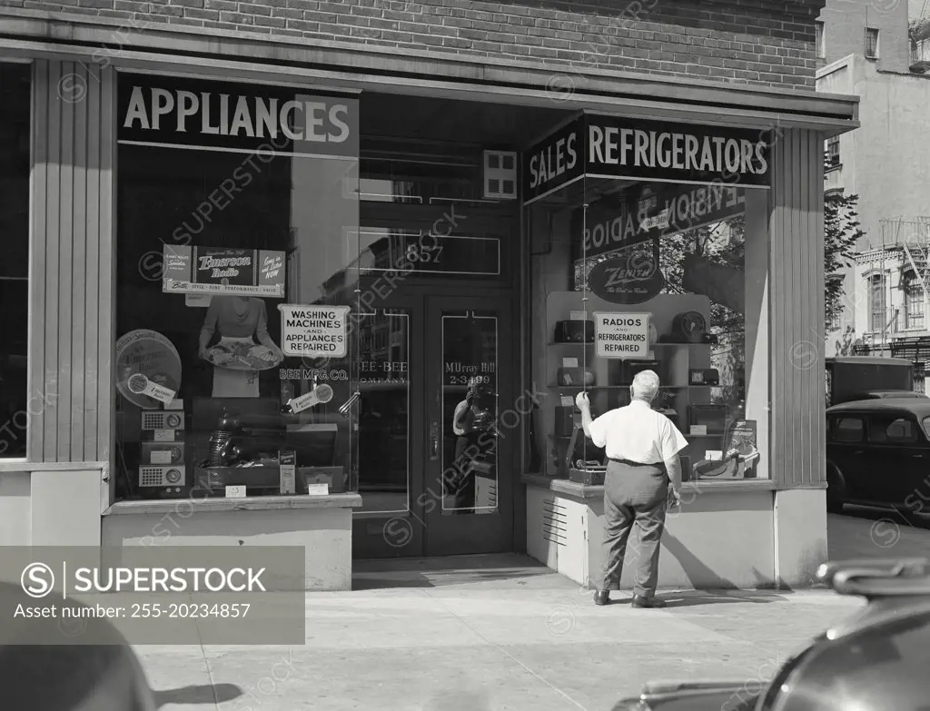 Exterior of Home Appliance store with man checking window of front display