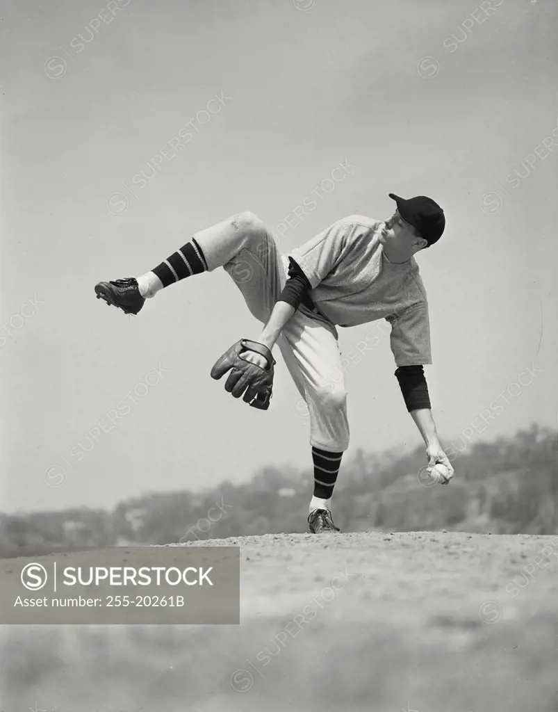 Side view of baseball pitcher with raised leg in windup before pitch