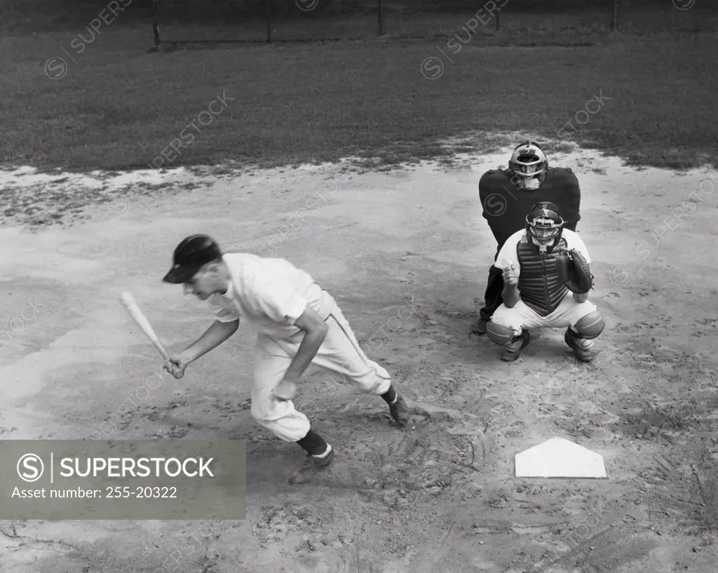 Two baseball players and a baseball umpire in a baseball field