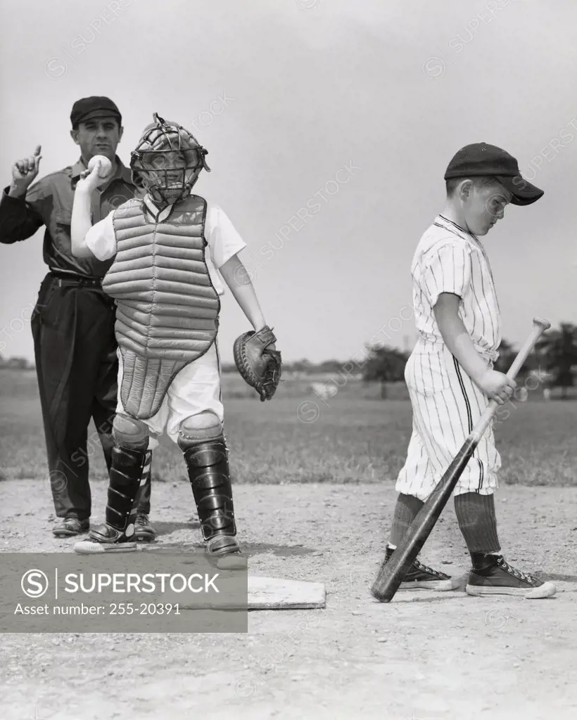 Two boys on a baseball field with a baseball umpire