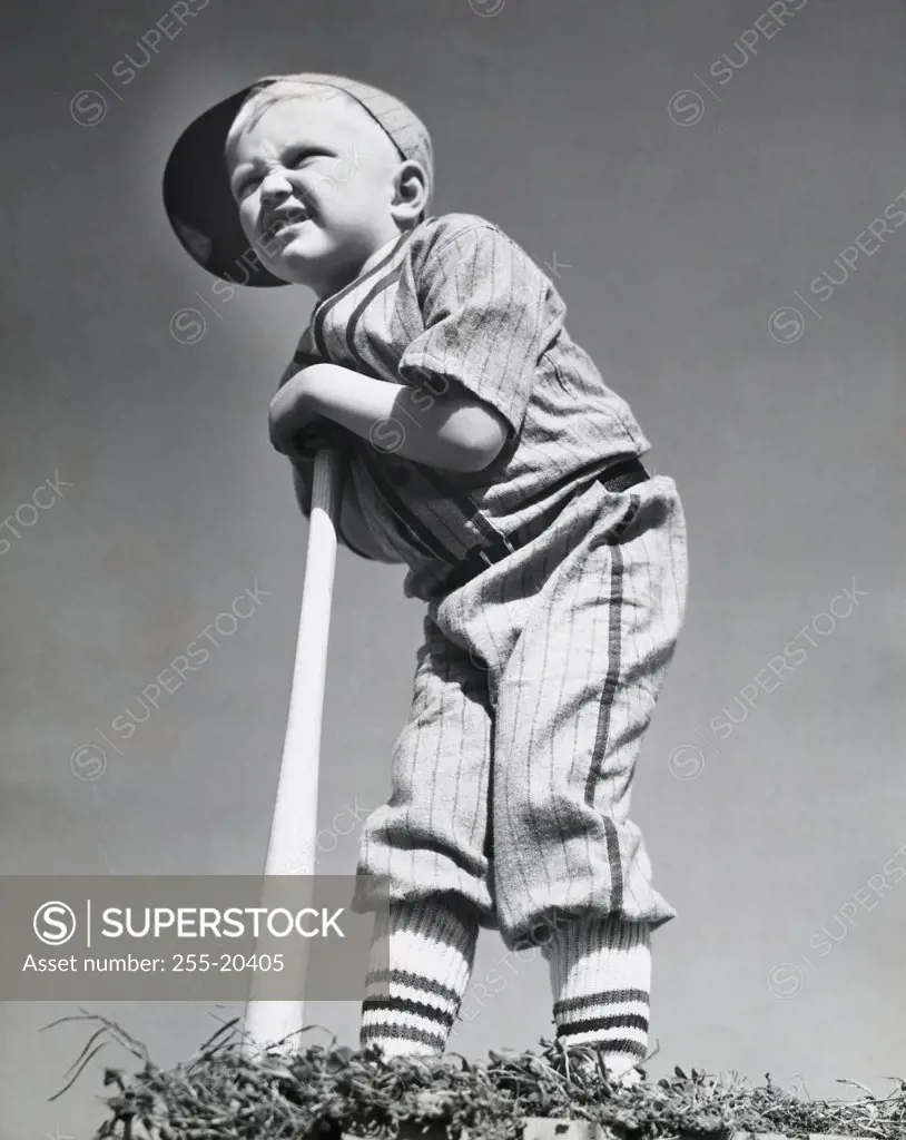 Low angle view of a boy leaning on a baseball bat