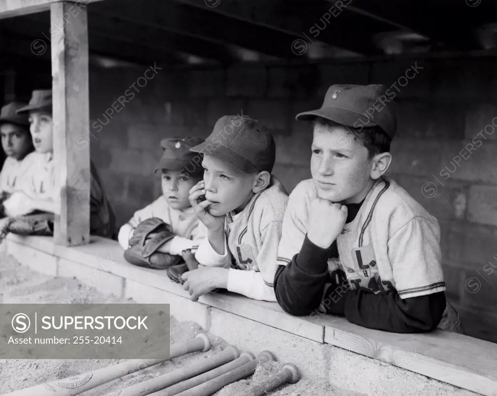 Youth league baseball players standing in a dugout