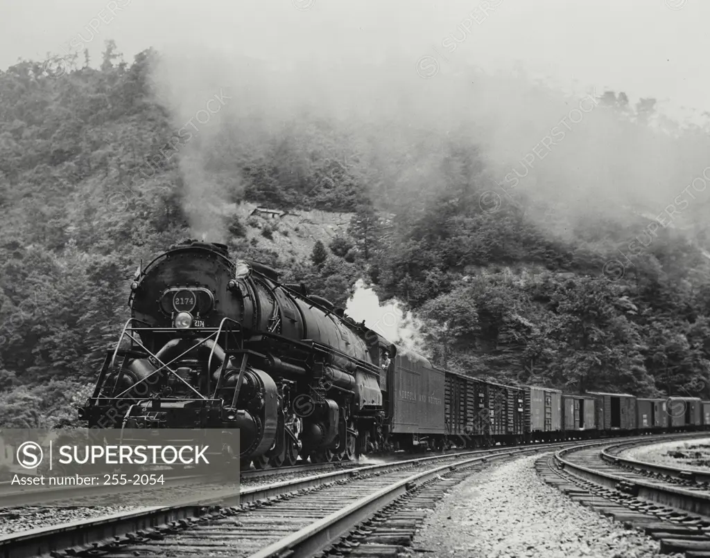 Vintage Photograph. Norjack + Western locomotive pulling freight cars going around bend.