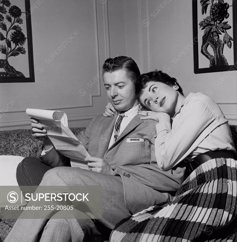 Young man reading bills with a young woman sitting beside him