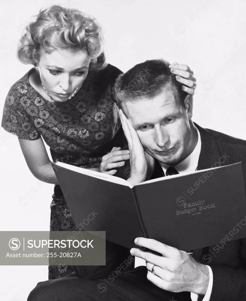 Close-up of a mid adult couple reading a family budget book