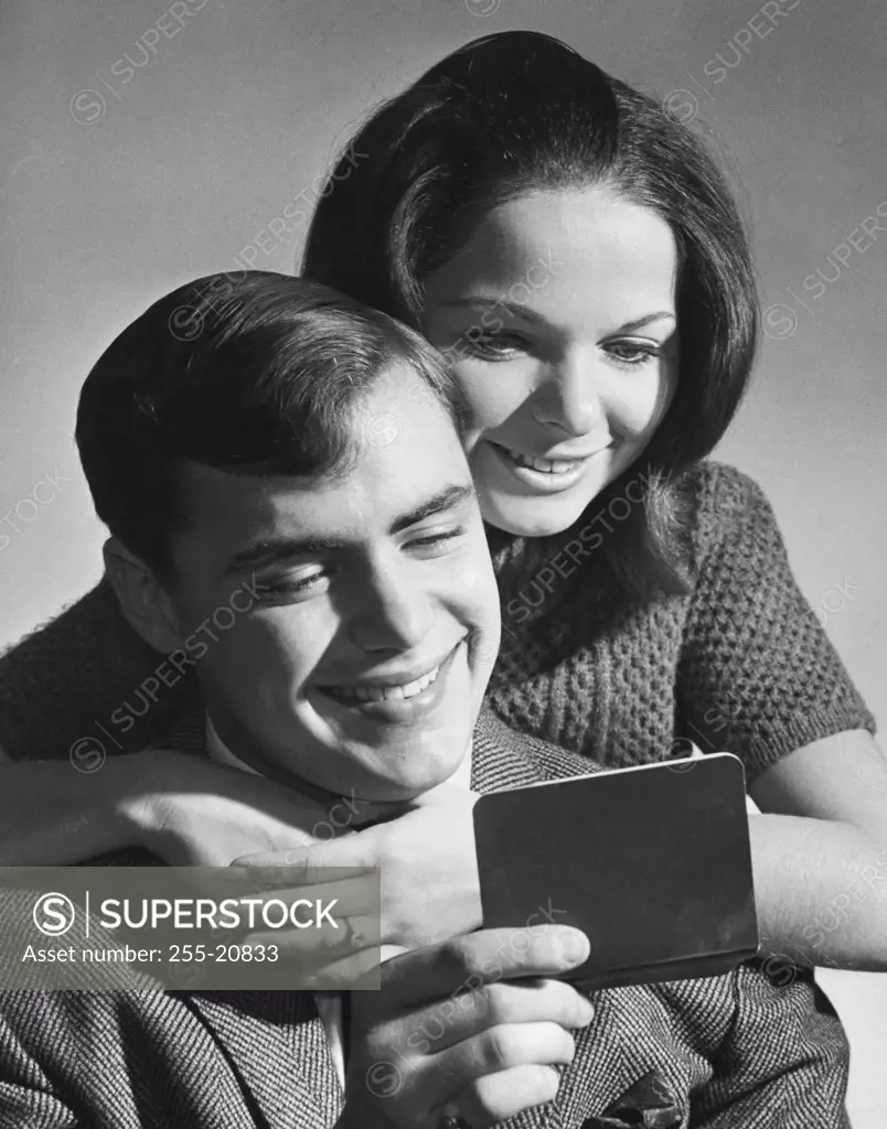 Close-up of a young couple reading a bankbook and smiling