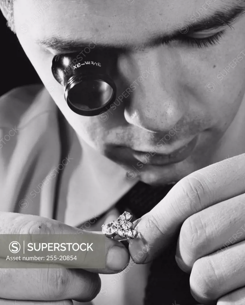 Close-up of a mid adult man inspecting a diamond ring