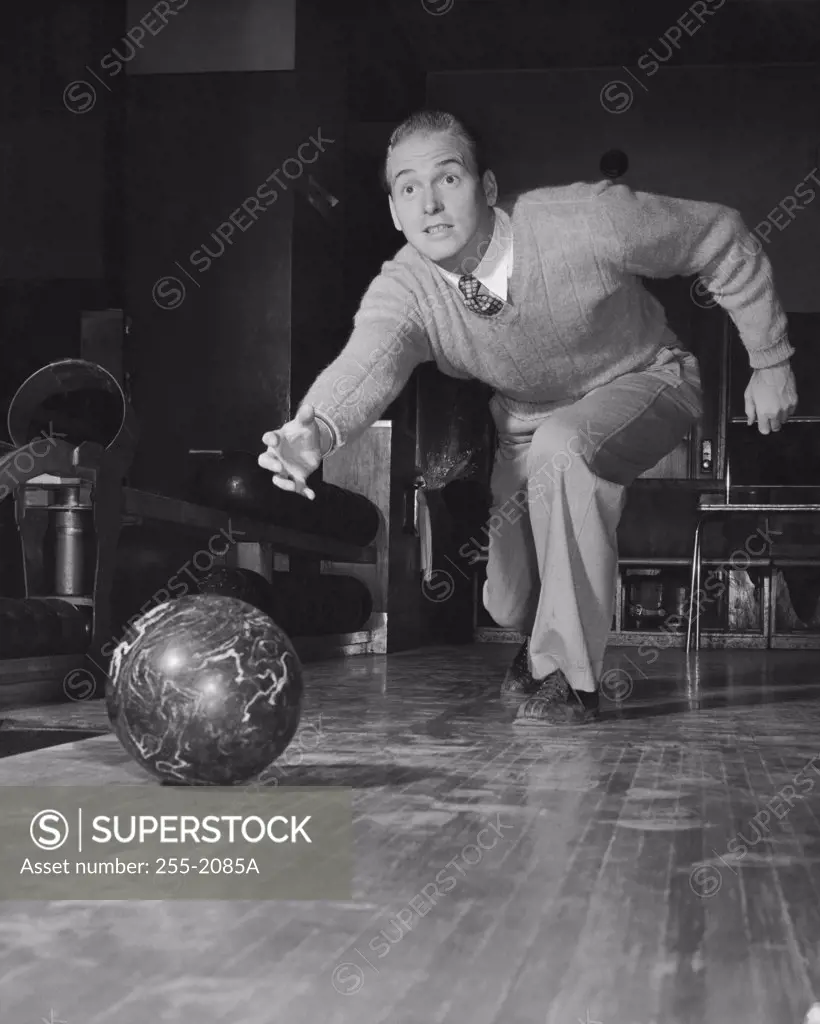 Vintage Photograph. Young adult man rolling bowling ball down lane