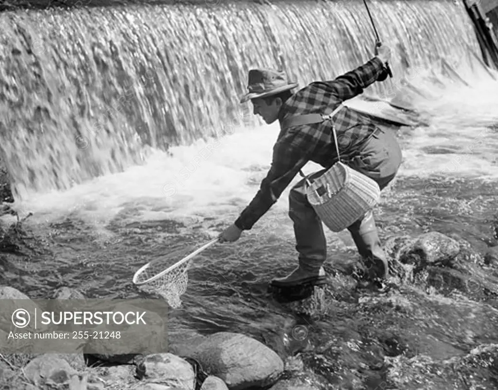 Mid adult man fly fishing in a river