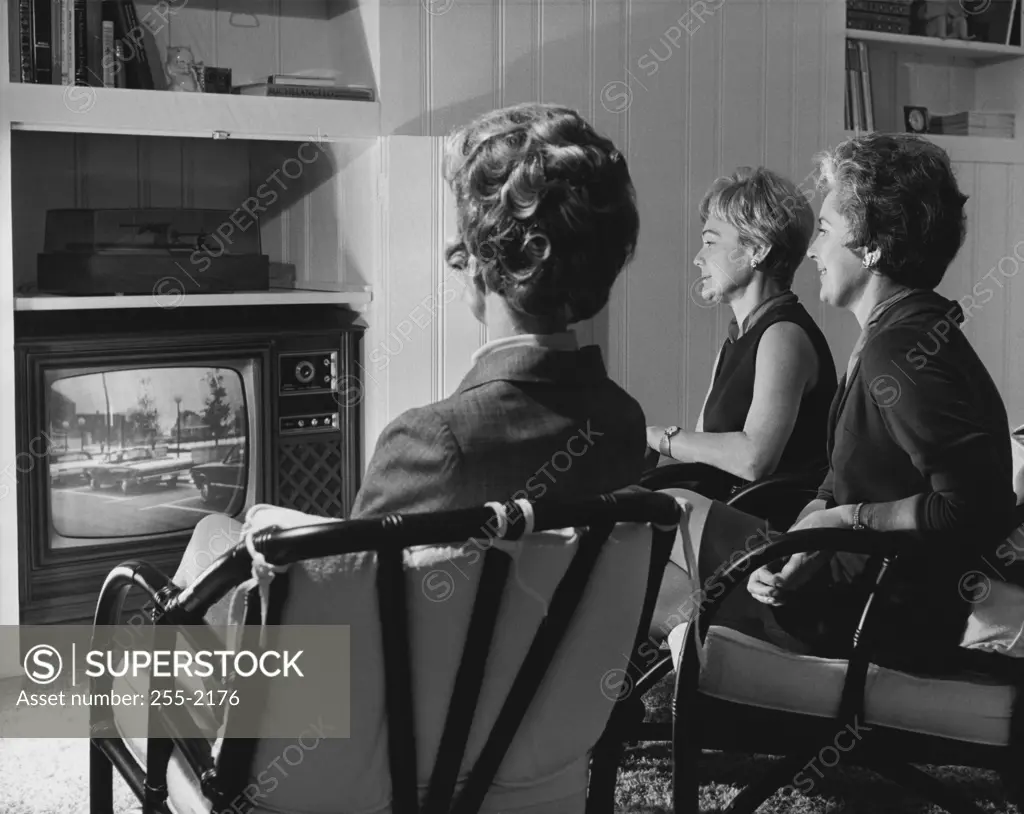Three mature women watching television
