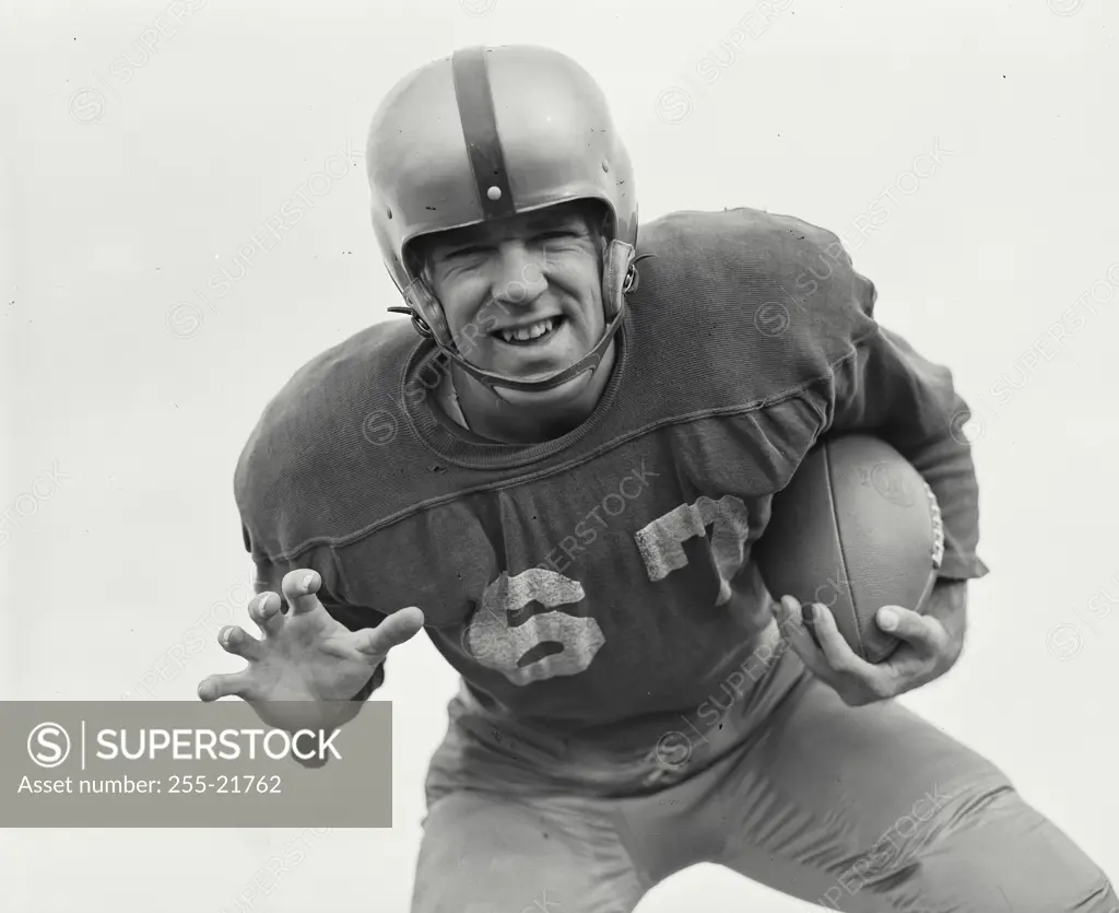 Vintage Photograph. Man in football uniform leaning down holding football with clawed hand