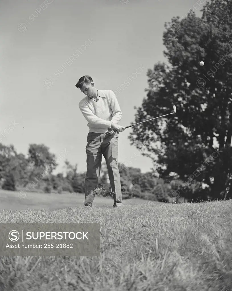 Vintage photograph. Mid adult man swinging golf club