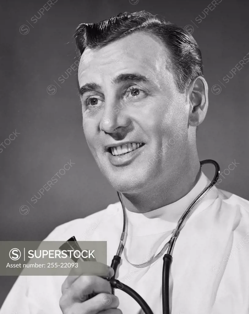 Vintage Photograph. Portrait of smiling man in doctors uniform holding stethoscope.