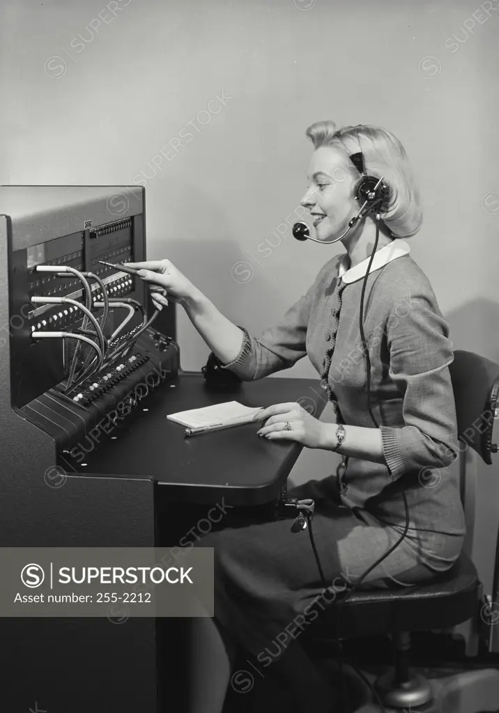 Vintage Photograph. Blonde woman switchboard operator smiling wearing headset and writing in notepad, Frame 8