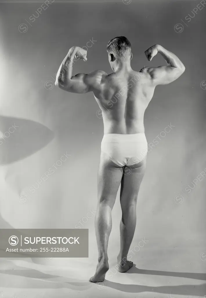 Vintage Photograph. Male bodybuilder striking pose in front of paper background, Frame 6