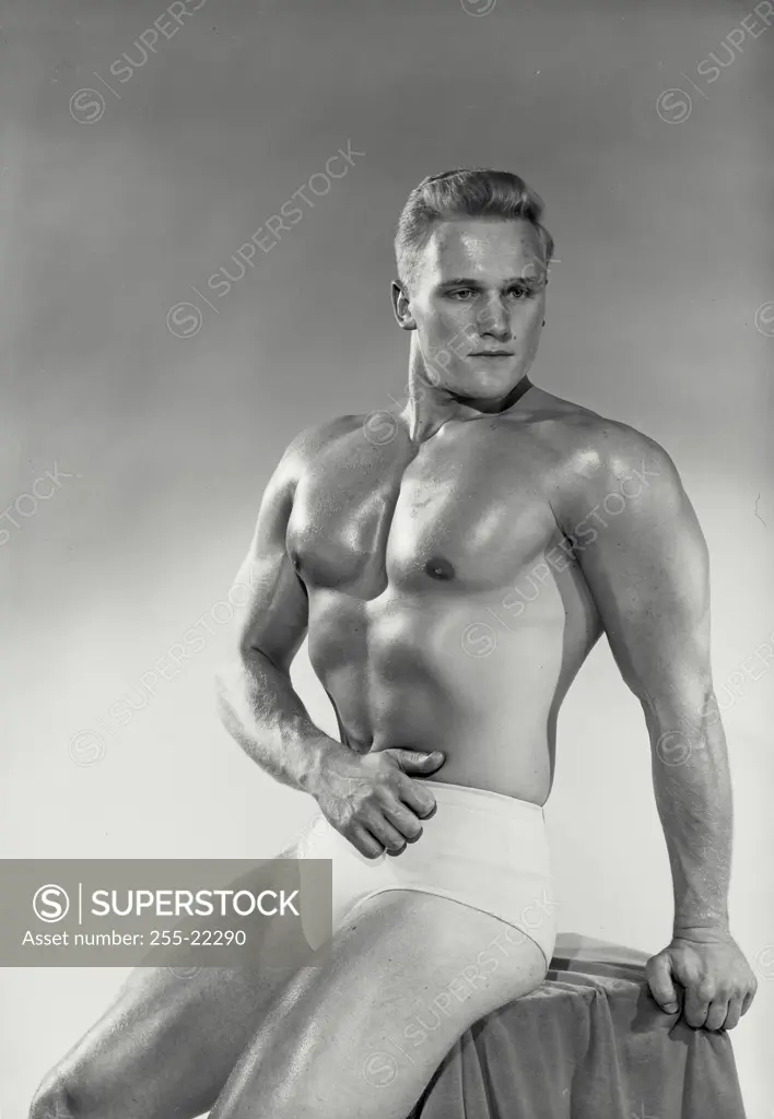 Vintage Photograph. Male bodybuilder sitting down striking pose, Frame 1
