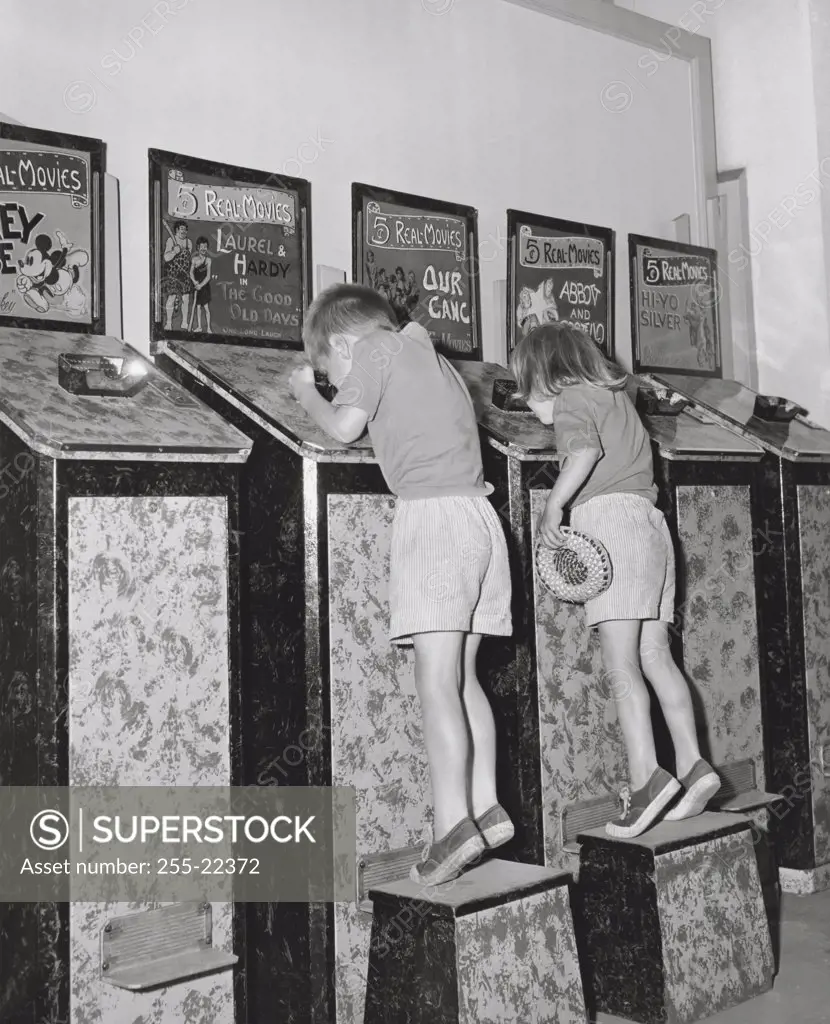 Two children looking into bioscopes at an amusement park, Playland, Rye, New York, USA