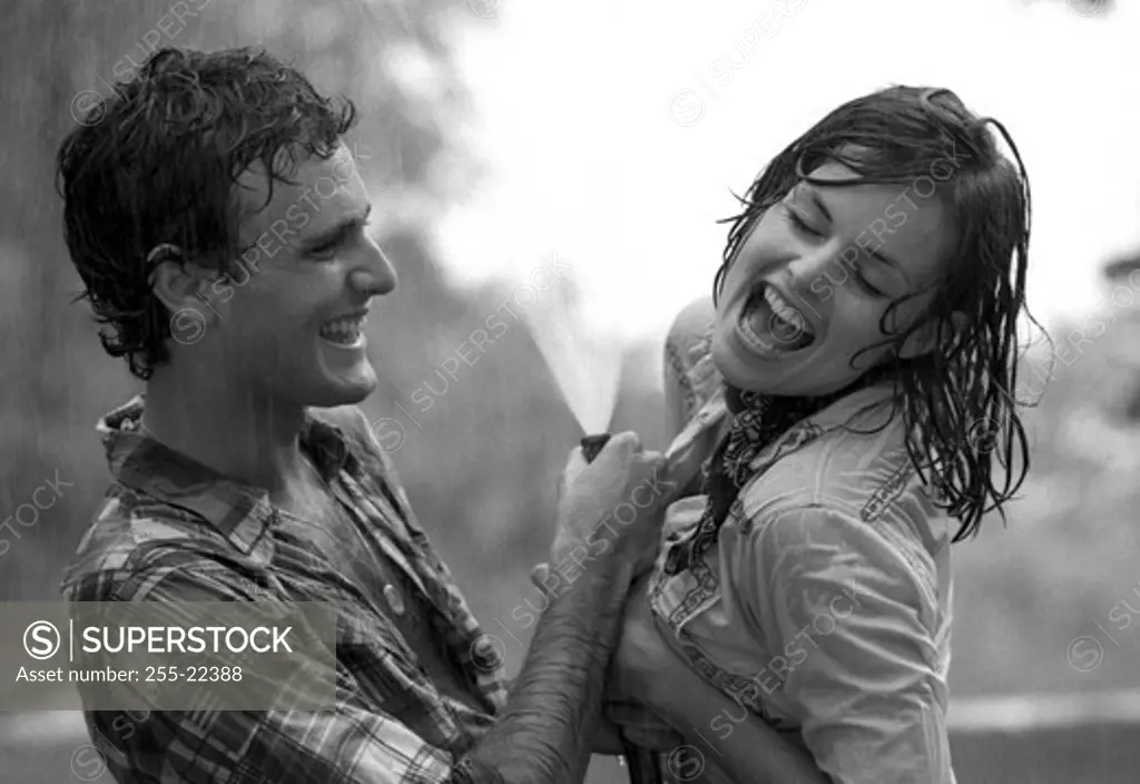Young couple playing with garden hose