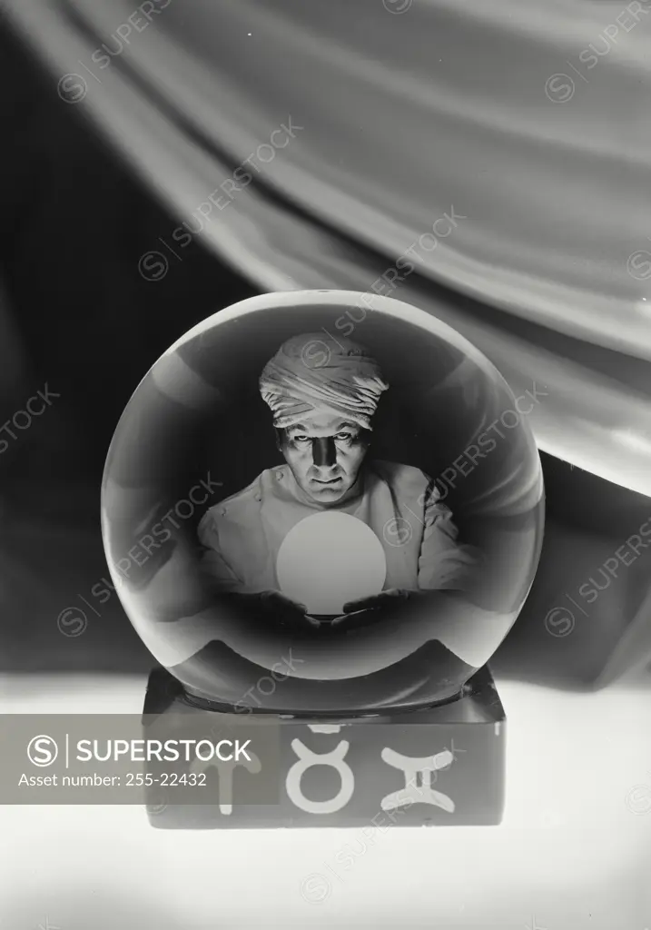 Vintage Photograph. Crystal ball showing fortune teller in center with fabric draped behind and symbols on base