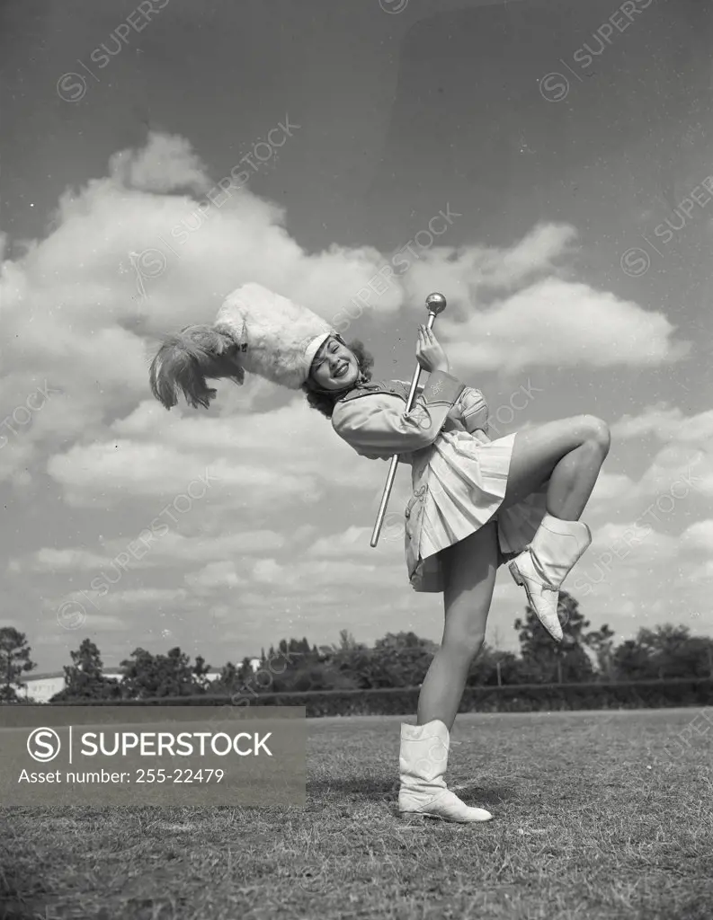 Vintage photograph. Drum majorette performing with a twirling baton in a field