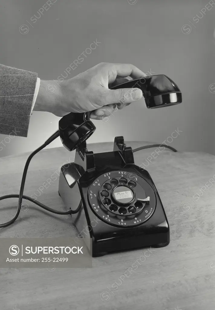 Vintage Photograph. Male hand picking up receiver of rotary telephone on wooden surface, Frame 4