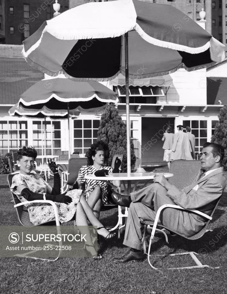 Side profile of a mid adult man sitting with two mid adult women on patio furniture