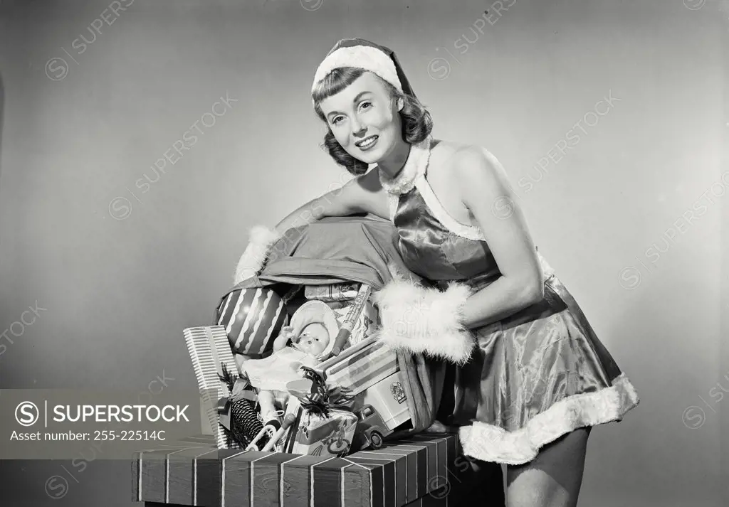 Vintage photograph. Portrait of a young woman dressed as santa dumping toys down chimney
