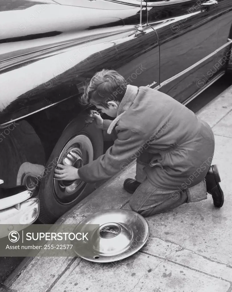 Boy stealing the hubcap of a car