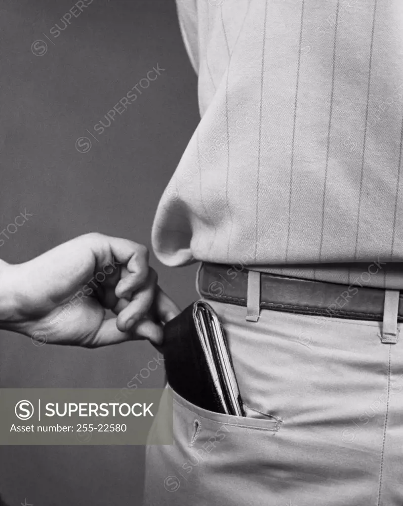 Close-up of a person's hand taking the wallet from a man's back pocket