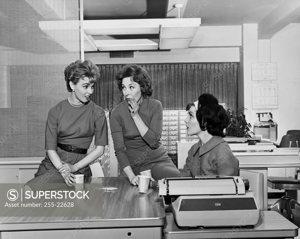 Three businesswomen gossiping in an office