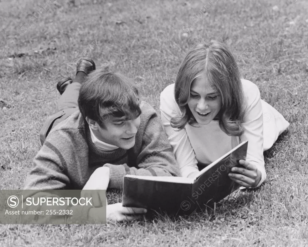 Teenage couple reading a book in a park