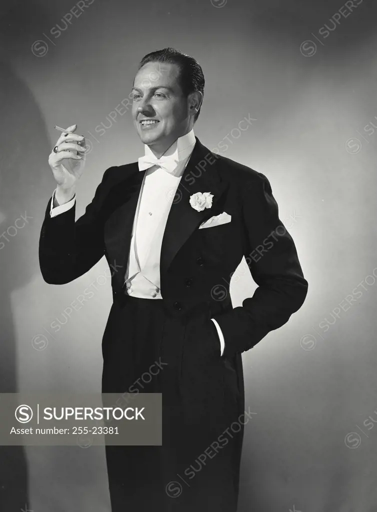 Vintage photograph. Man in tuxedo holding up cigarette