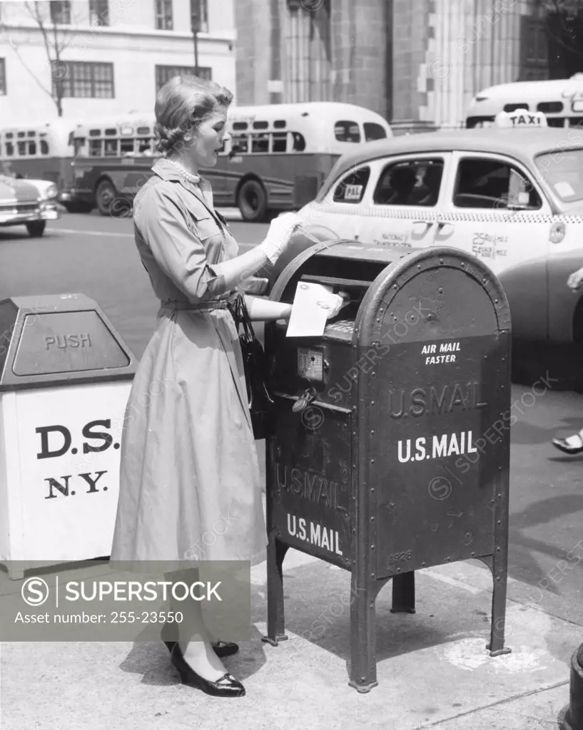 Side profile of a mid adult woman dropping mail in a mailbox