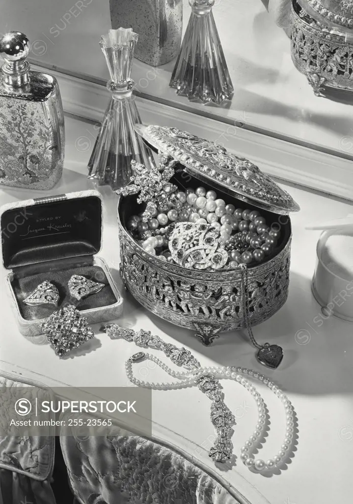 Vintage photograph. Ornate jewelry box full of necklaces and earrings on vanity stand with earring box