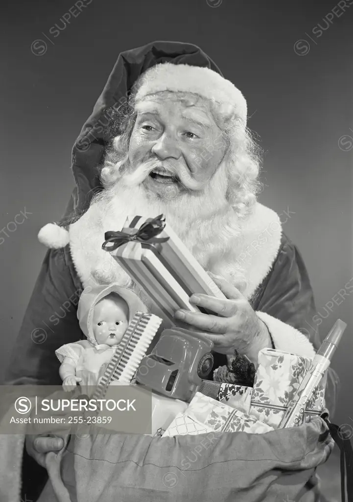 Vintage photograph. Close-up of man in Santa Claus costume with sack full of children's toys