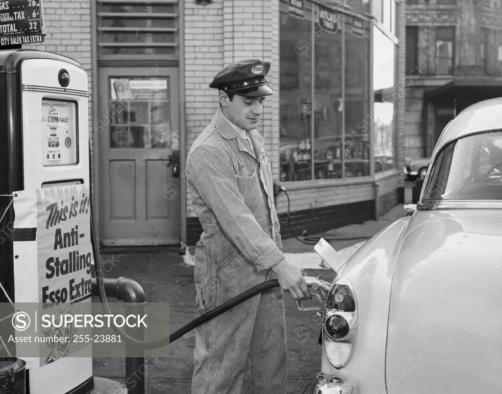 Side profile of a gas station attendant filling up a car