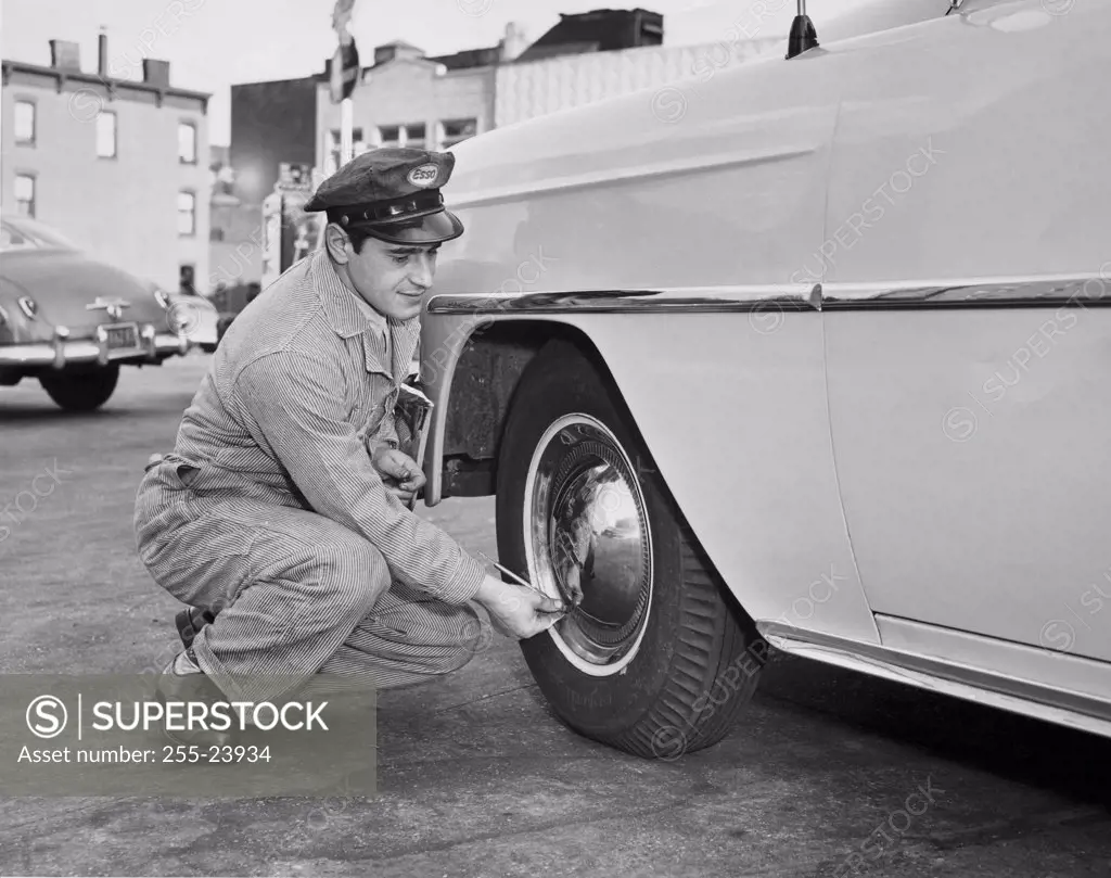 Gas station attendant checking air pressure of a car tire