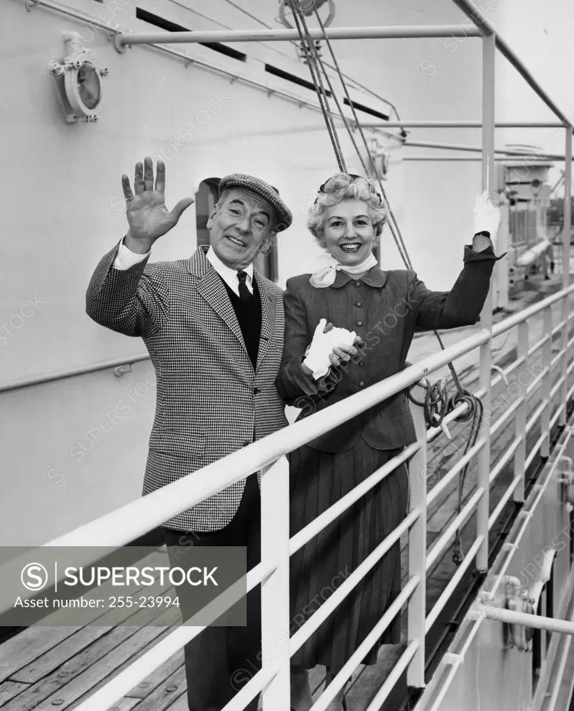 Portrait of a senior couple standing on a ship waving