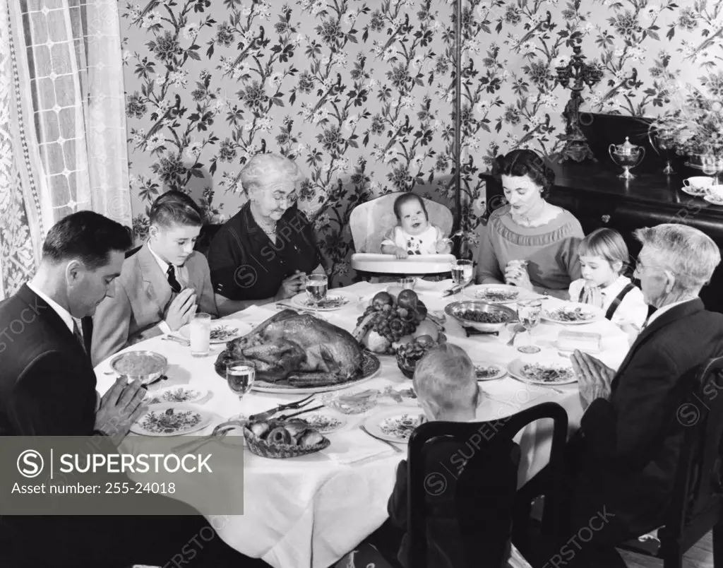 Family praying at dining table on Thanksgiving Day