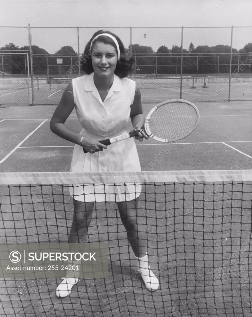 Young woman standing on a tennis court and holding a tennis racket