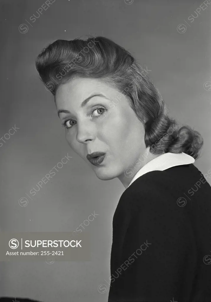 Vintage Photograph. Woman with styled blonde hair wearing black blouse with white collar with surprised expression on face