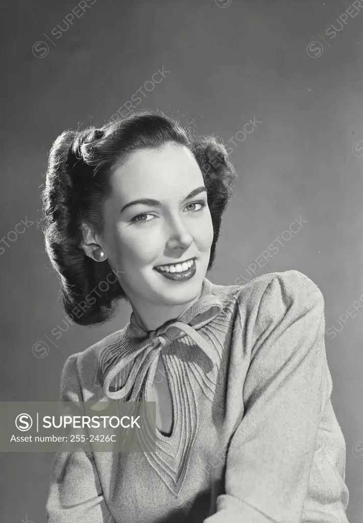 Pretty brunette woman wearing sweater blouse with tie on collar smiling