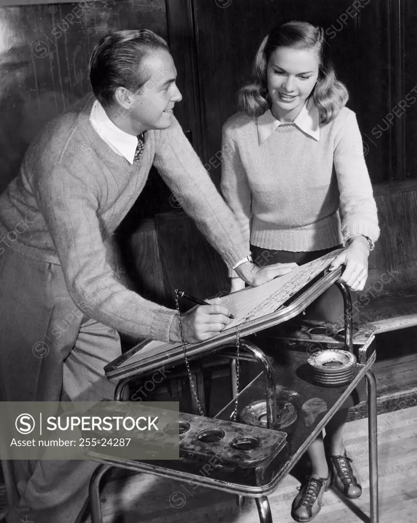 Vintage Photograph. Man and woman keeping track of score for a bowling game