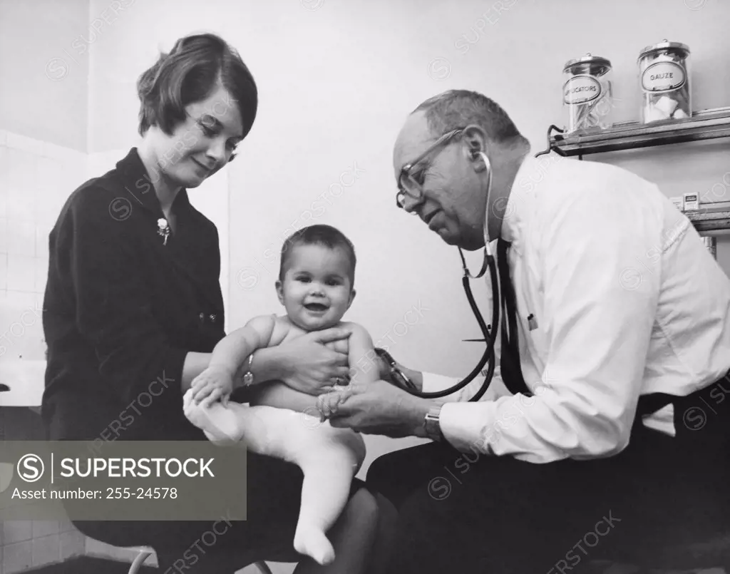 Side profile of a male doctor examining a baby boy