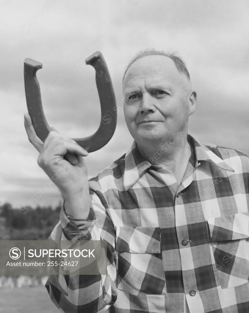 Mature man holding a horseshoe