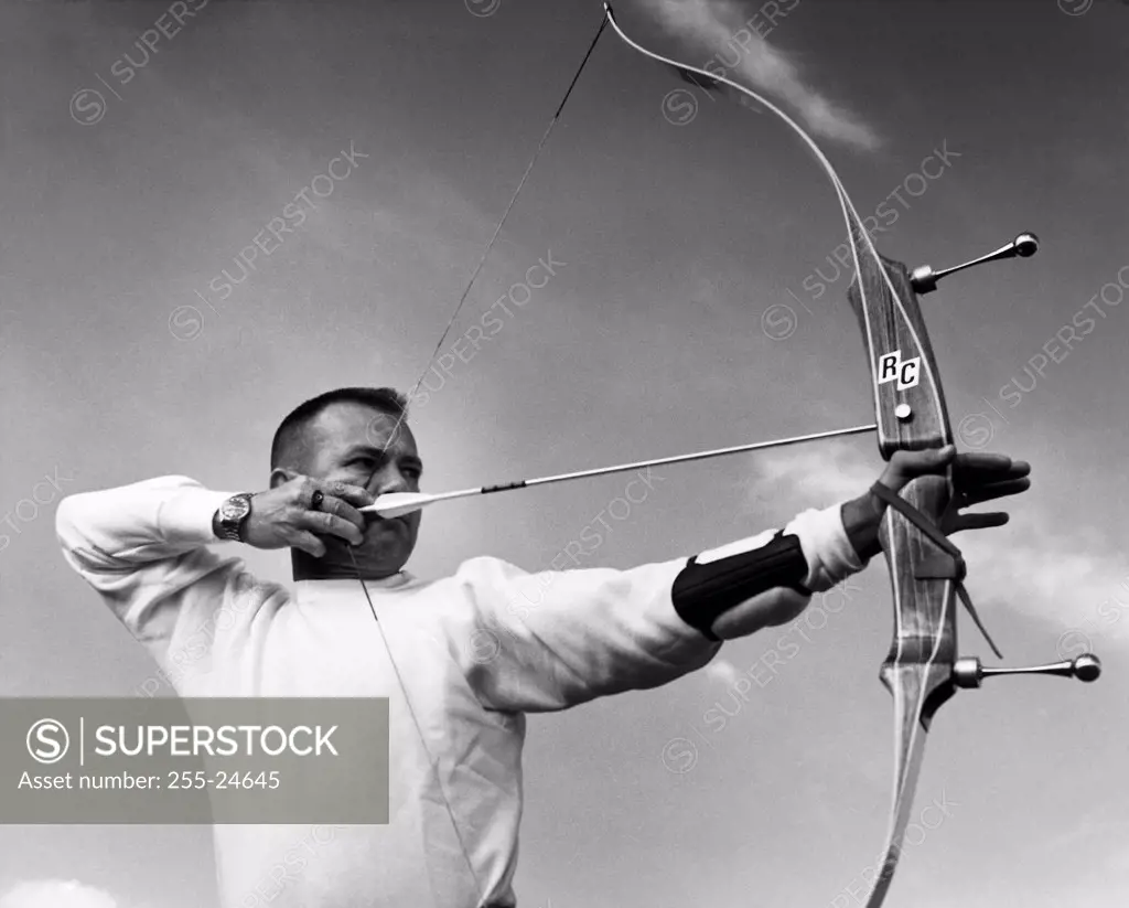 Mid adult man aiming with a bow and arrow