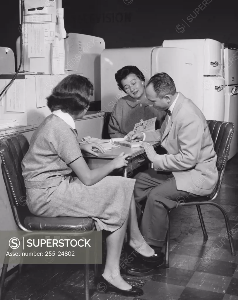 Side profile of a salesman sitting with two female customers in a store